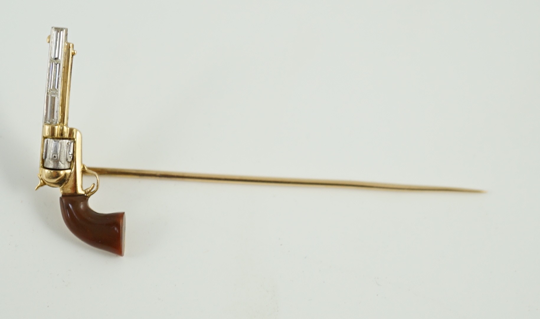 A Cartier 18k gold, platinum and six stone baguette cut diamond set novelty stick pin, modelled and a pistol inscribed 'Peacemaker'